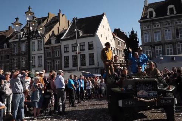 A group of people ride in a car surrounded by a large crowd.